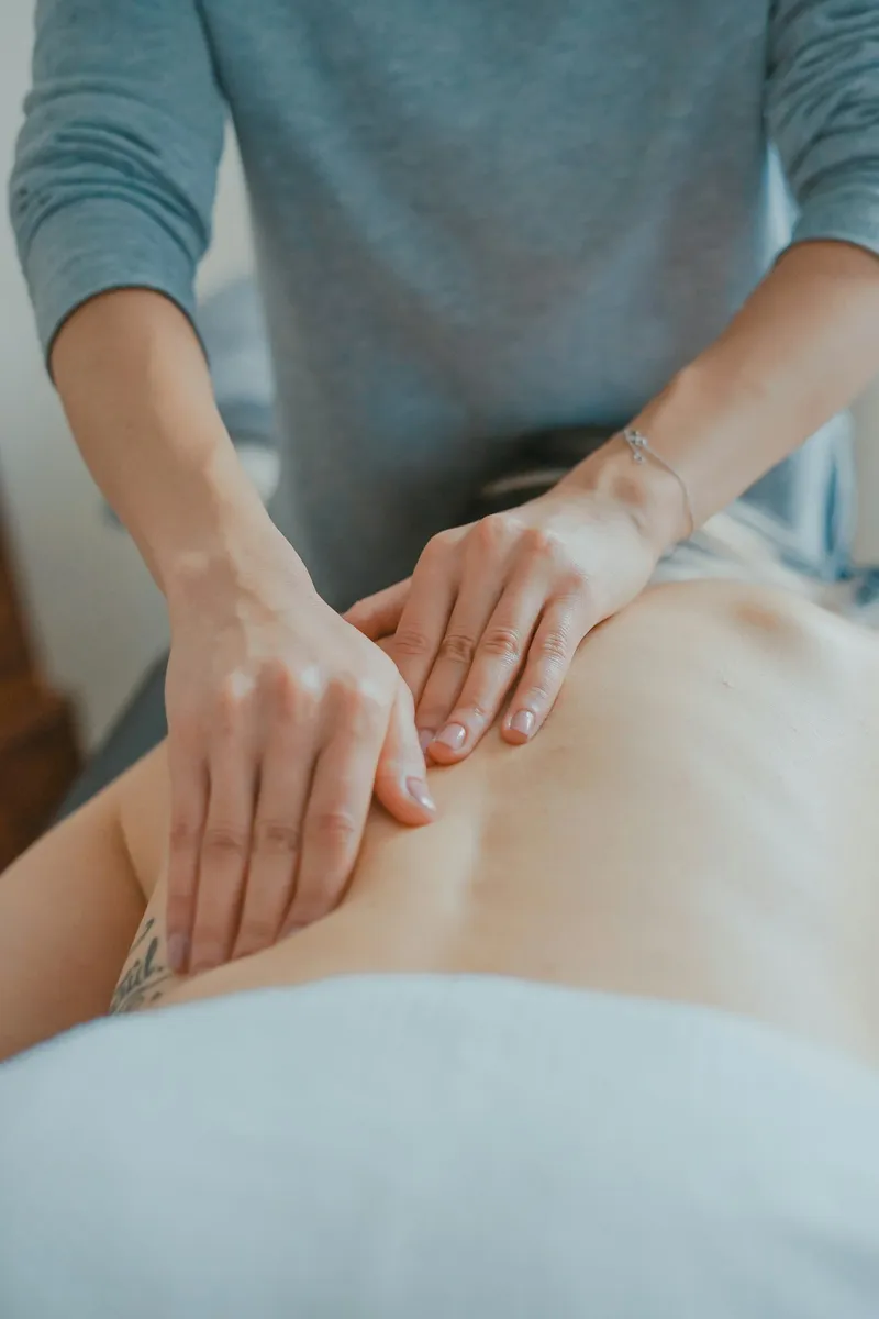 Manos de una terapeuta presionan la espalda baja de una persona recostada